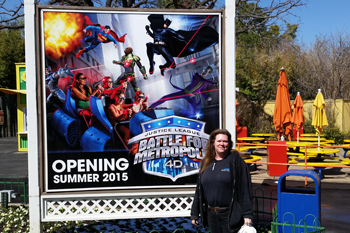 Field Technician Lisa Hasen in front of Opening Soon sign for Interactive dark ride Justice League: Battle For Metropolis 4D at Six Flags Theme Park, U.S.A.