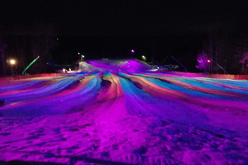 vibrant colors of pink, purple, red royal blue and aqua from LED fixutres illuminating the snow at Lunar Lights Tubing Peek 'n Peak Resort - Clymer, New York U.S.A.