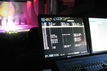 SGM Reiga 2048 Pro console with program of the show, full seated audience in the background watching a performance on a brightly lit stage in hues of yellows whites and pinks at Glamur, Sexo, Divas y Otras Mentiras - Teatro Nacional, Dominican Republic